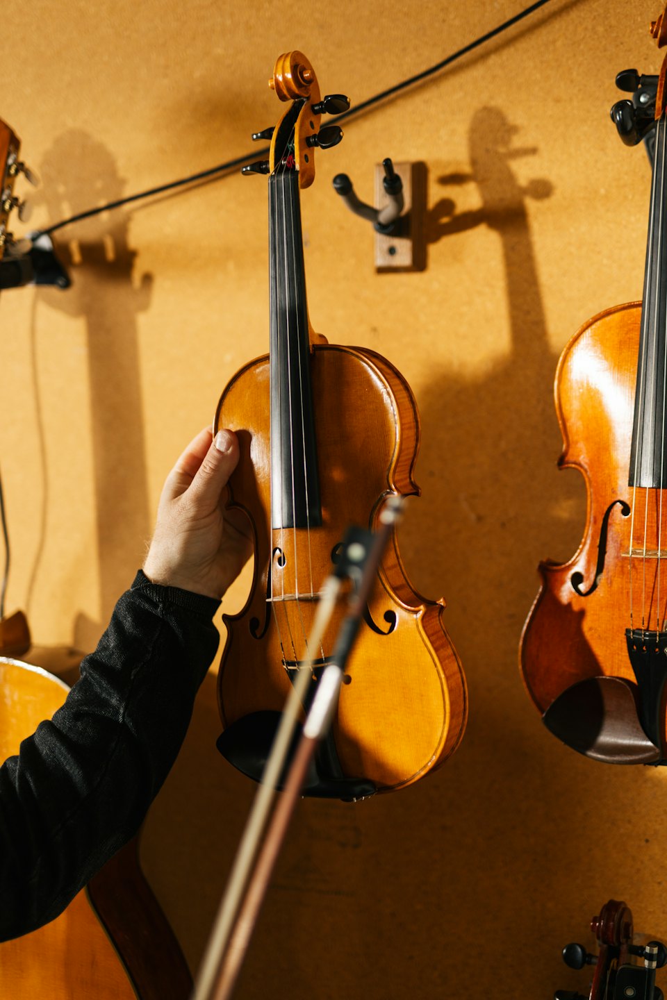 Una persona tocca un violino di legno appeso al muro.