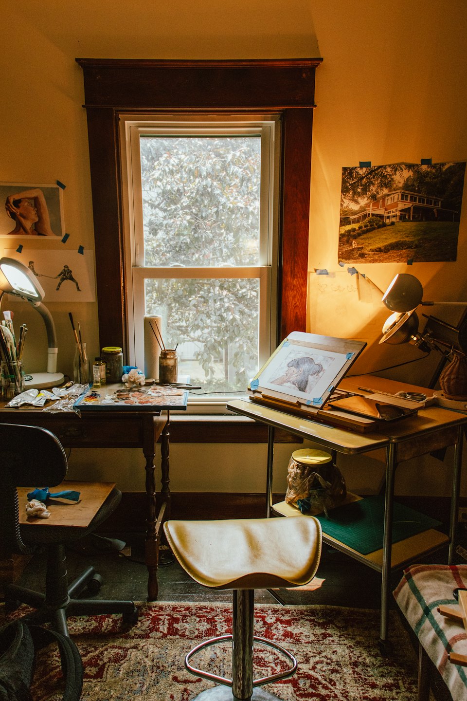 Studio d'artista con scrivania disordinata e cavalletto su un tavolo da disegno.