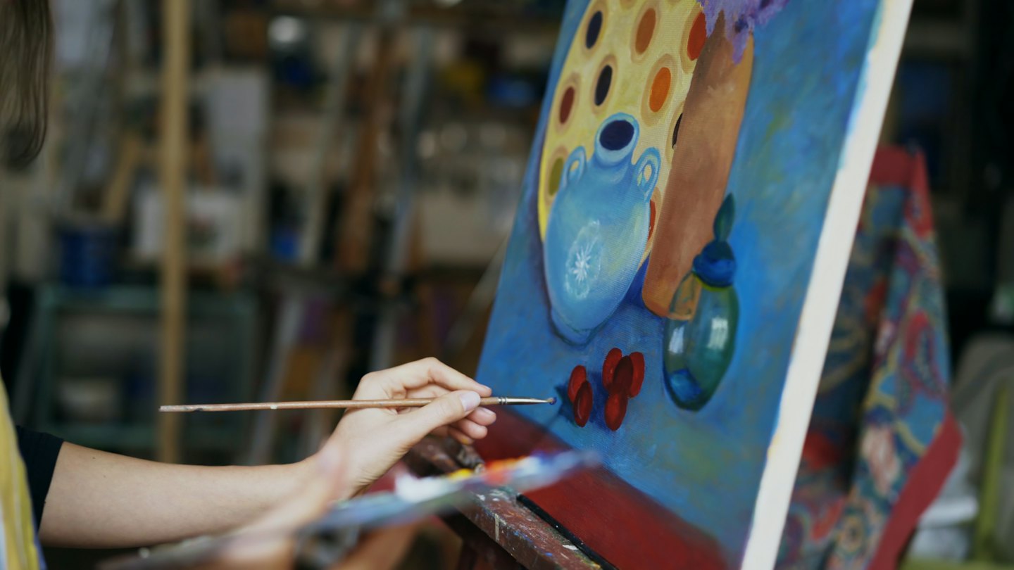 Un artista dipinge una natura morta su tela con un pennello.